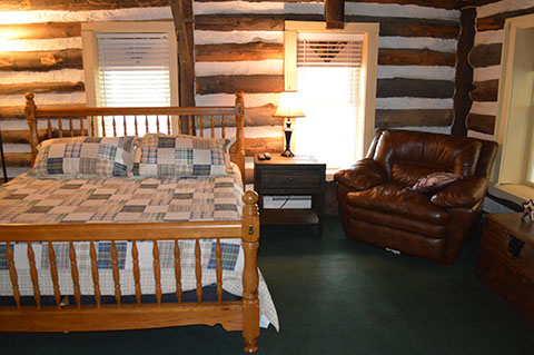 A rustic Log living room offers a place to relax as well as extra room to sleep with the sleeper sofa.